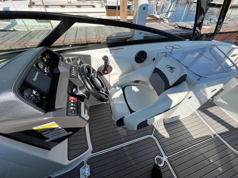 Slide: The Image of 2019 Monterey M6 boat interior with steering wheel, dashboard, and seating at a marina. - 5
