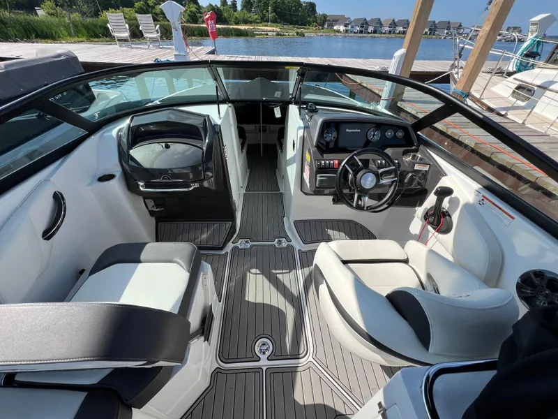 Slide: The Image of 2019 Monterey M6 boat interior with sleek seating and modern dashboard at a dock. - 6