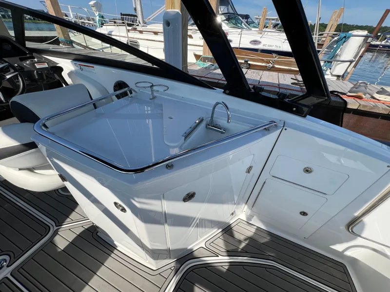 Slide: The Image of 2019 Monterey M6 boat interior with sleek white cabinetry and modern fixtures at a marina. - 7
