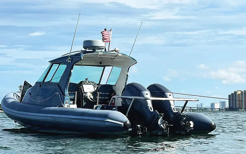 Slide: The Image of 2000 Protector Targa 28 boat with dual engines on calm water, city skyline in background. - 3