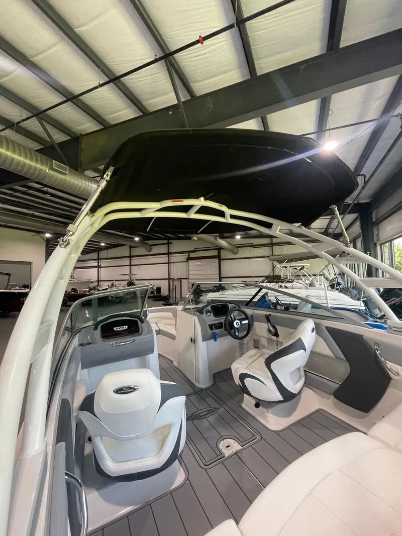 Slide: The Image of 2023 Chaparral 21 SSi OB boat interior with modern seating and dashboard in a showroom. - 11