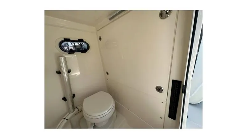 Slide: The Image of 2024 Sea Born FX25 Bay boat interior with compact marine toilet and porthole window. - 26