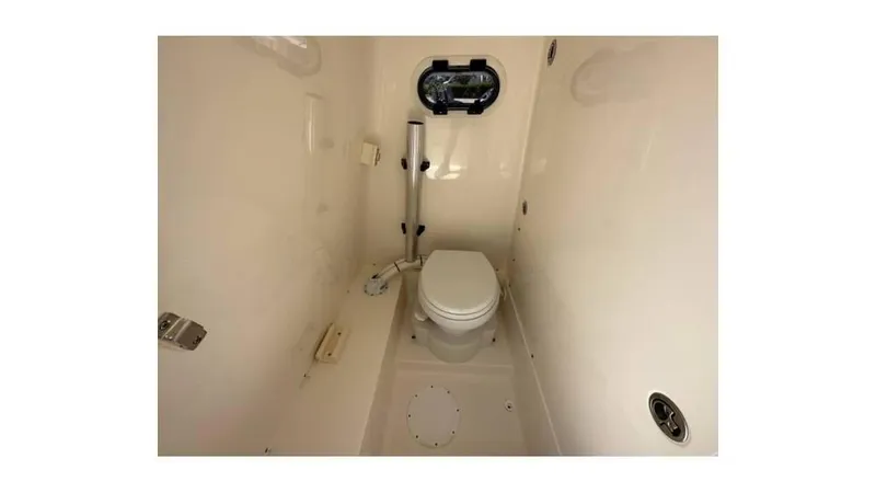 Slide: The Image of 2024 Sea Born FX25 Bay boat interior with compact marine toilet and porthole. - 27