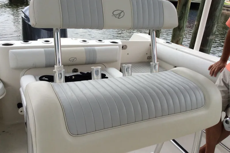 Slide: The Image of 2011 Sailfish Center Console boat seating with rod holders, docked by water. - 11