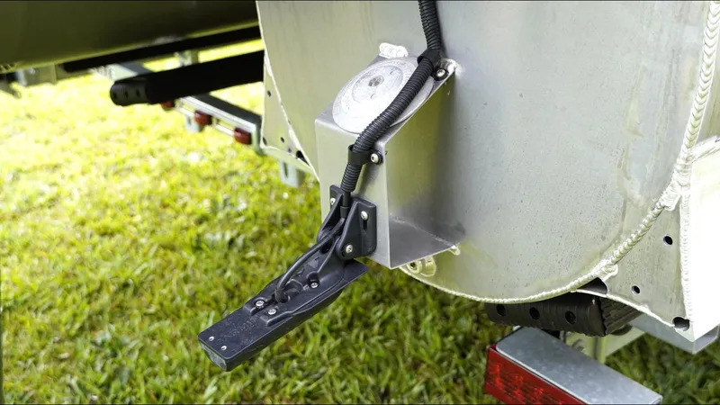 Slide: The Image of 2025 SunCatcher Fusion 324SS boat detail, showing metal component and wiring on grassy background. - 26