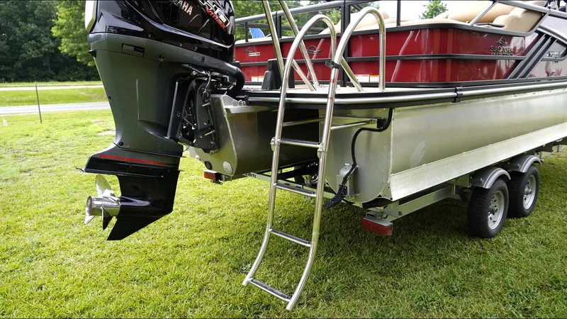 Slide: The Image of 2025 SunCatcher Fusion 324SS boat with ladder and outboard motor on grass. - 27