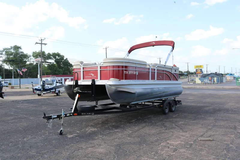 Slide: The Image of 2013 Bennington 22 SLX pontoon boat on trailer, parked in a lot under a clear sky. - 3