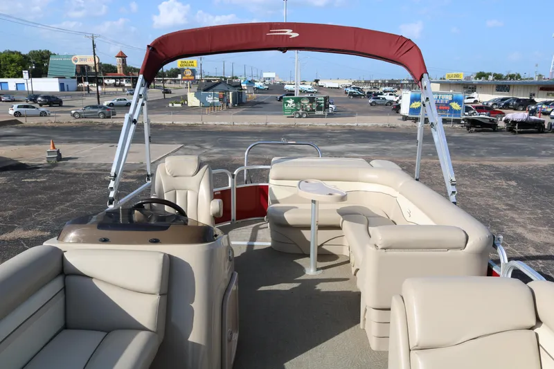 Slide: The Image of 2013 Bennington 22 SLX pontoon boat with beige seating and red canopy in a parking lot. - 9
