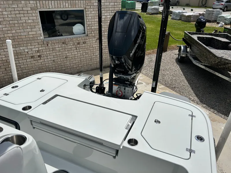 Slide: The Image of 2026 Caymas 28 HB boat with Mercury outboard engine, parked near a brick wall. - 15