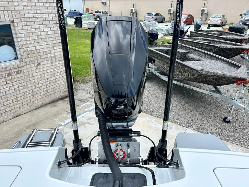 Slide: The Image of 2026 Caymas 28 HB boat with Power-Pole anchors and outboard motor in a parking area. - 17
