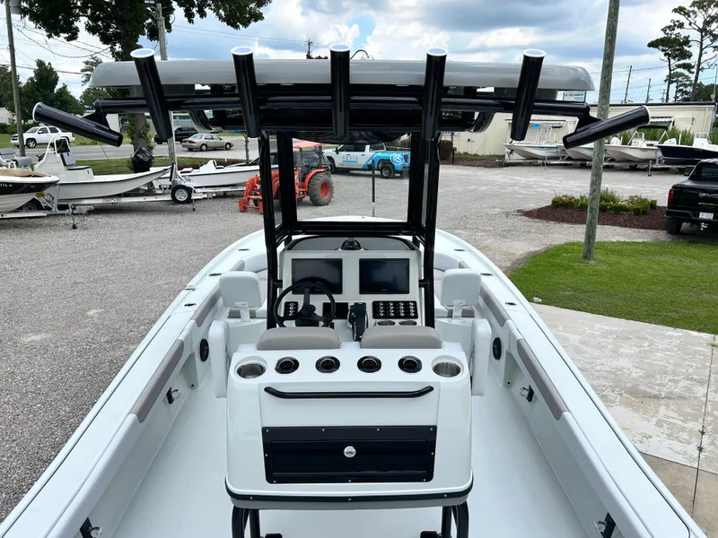 Slide: The Image of 2026 Caymas 28 HB boat interior with steering console and rod holders, parked outdoors. - 19