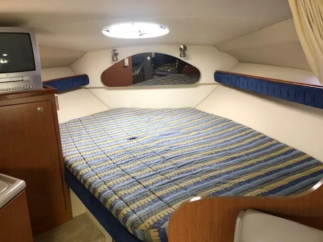 Slide: The Image of 2004 Cruisers Yachts 280 Express cabin with bed, TV, and porthole window. - 14