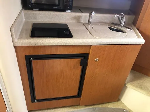 Slide: The Image of 2004 Cruisers Yachts 280 Express galley with sink, stove, and compact fridge. - 16
