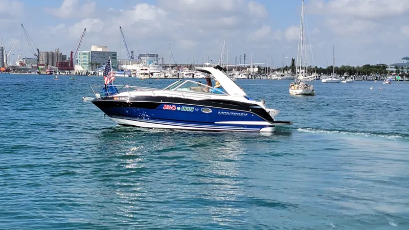 The Image of 2019 Monterey 295 Sport Yacht cruising in a busy harbor with cityscape background. - 0