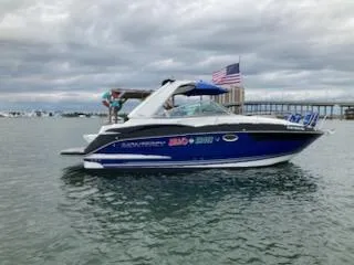 Slide: The Image of 2019 Monterey 295 Sport Yacht on water, American flag, cloudy sky. - 1