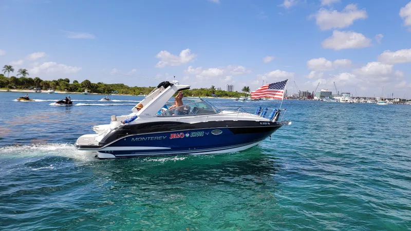 Slide: The Image of 2019 Monterey 295 Sport Yacht cruising on clear blue water with American flag. - 23