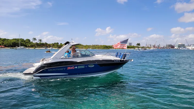 Slide: The Image of 2019 Monterey 295 Sport Yacht cruising on clear blue water with American flag. - 24