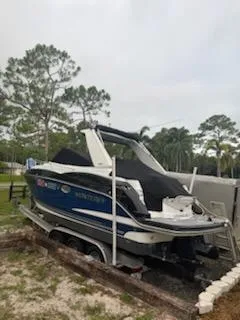 Slide: The Image of 2019 Monterey 295 Sport Yacht on trailer, parked outdoors with trees in background. - 6