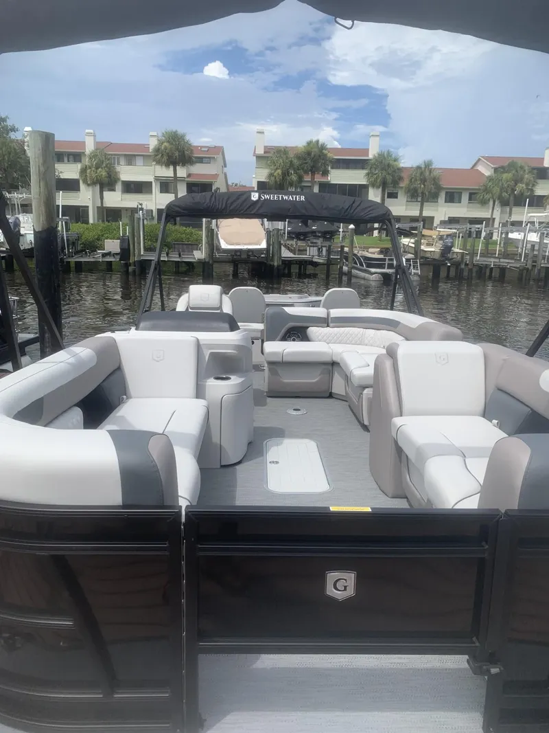 Slide: The Image of 2026 Godfrey Sweetwater 2286 FS pontoon boat with spacious seating, docked near waterfront homes. - 9