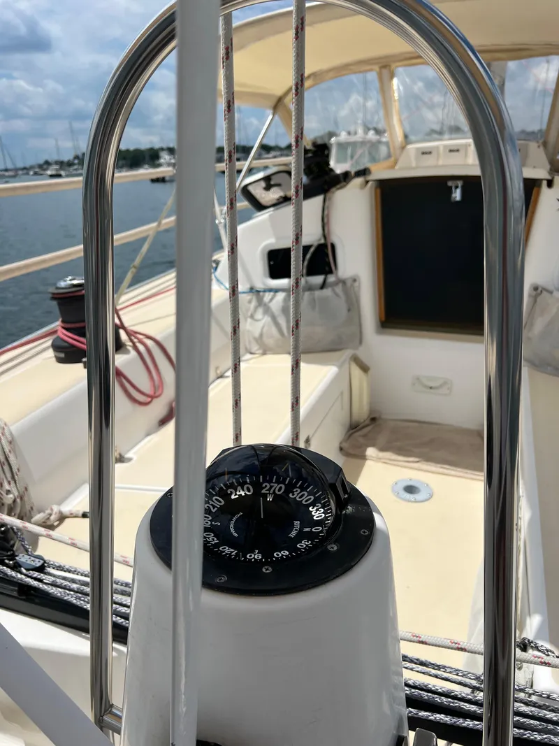 Slide: The Image of 2001 J Boats J/120 sailboat cockpit with compass, ropes, and sunny marina view. - 15