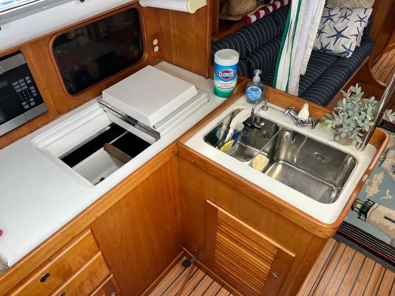 Slide: The Image of 2001 J Boats J/120 yacht kitchen with sink, storage, and cleaning supplies. - 19