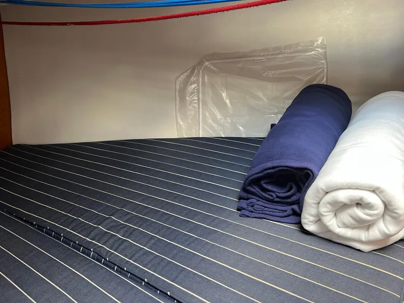 Slide: The Image of Interior of 2001 J Boats J/120 with striped bedding and rolled linens. - 25