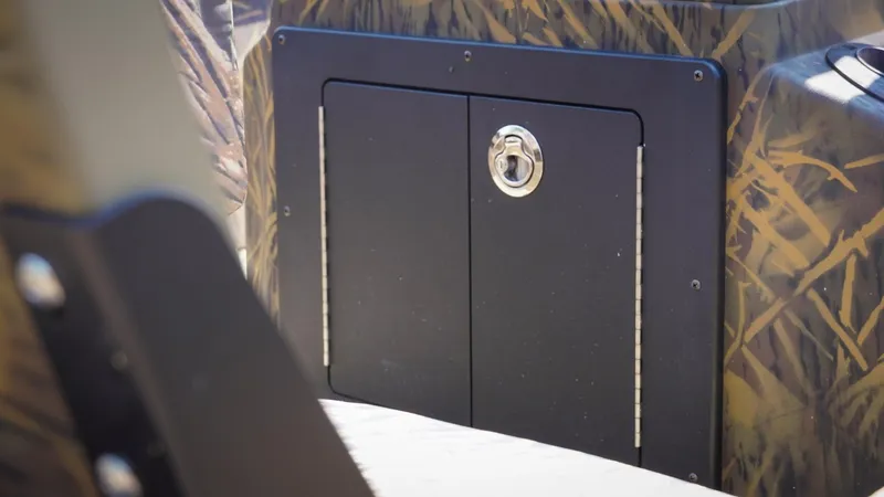 Slide: The Image of 2025 G3 Gator Tough 20 CC boat storage compartment with camo design and secure latch. - 8
