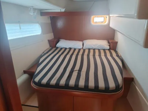 Slide: The Image of Cozy cabin interior of 2011 Leopard 46 yacht with striped bedding and porthole window. - 8