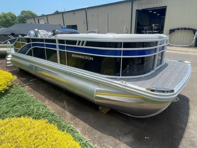 Slide: The Image of 2024 Bennington 22SXSWB pontoon boat parked outdoors near a warehouse. - 3