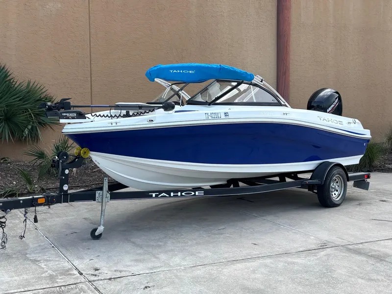 Slide: The Image of 2021 Tahoe 550TF boat on trailer, blue and white design, parked outdoors. - 7