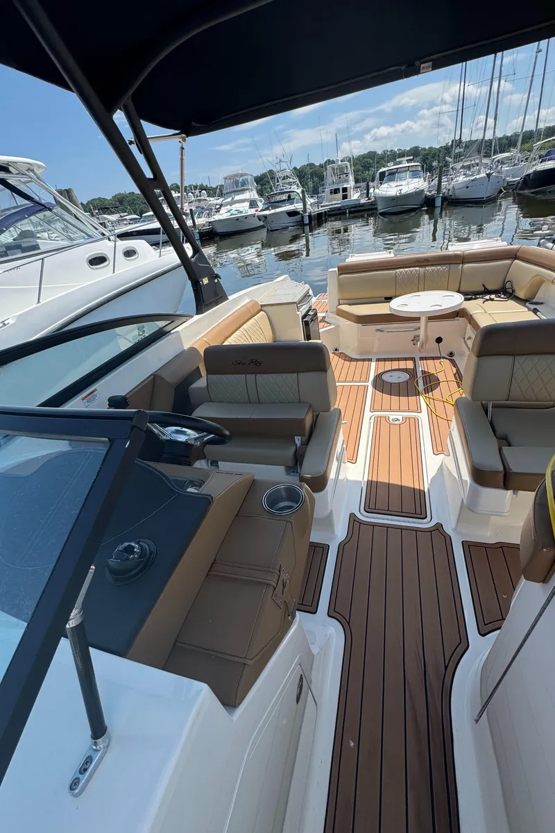 Slide: The Image of 2015 Sea Ray 290 Sundeck boat interior with seating, table, and wood flooring at marina. - 10
