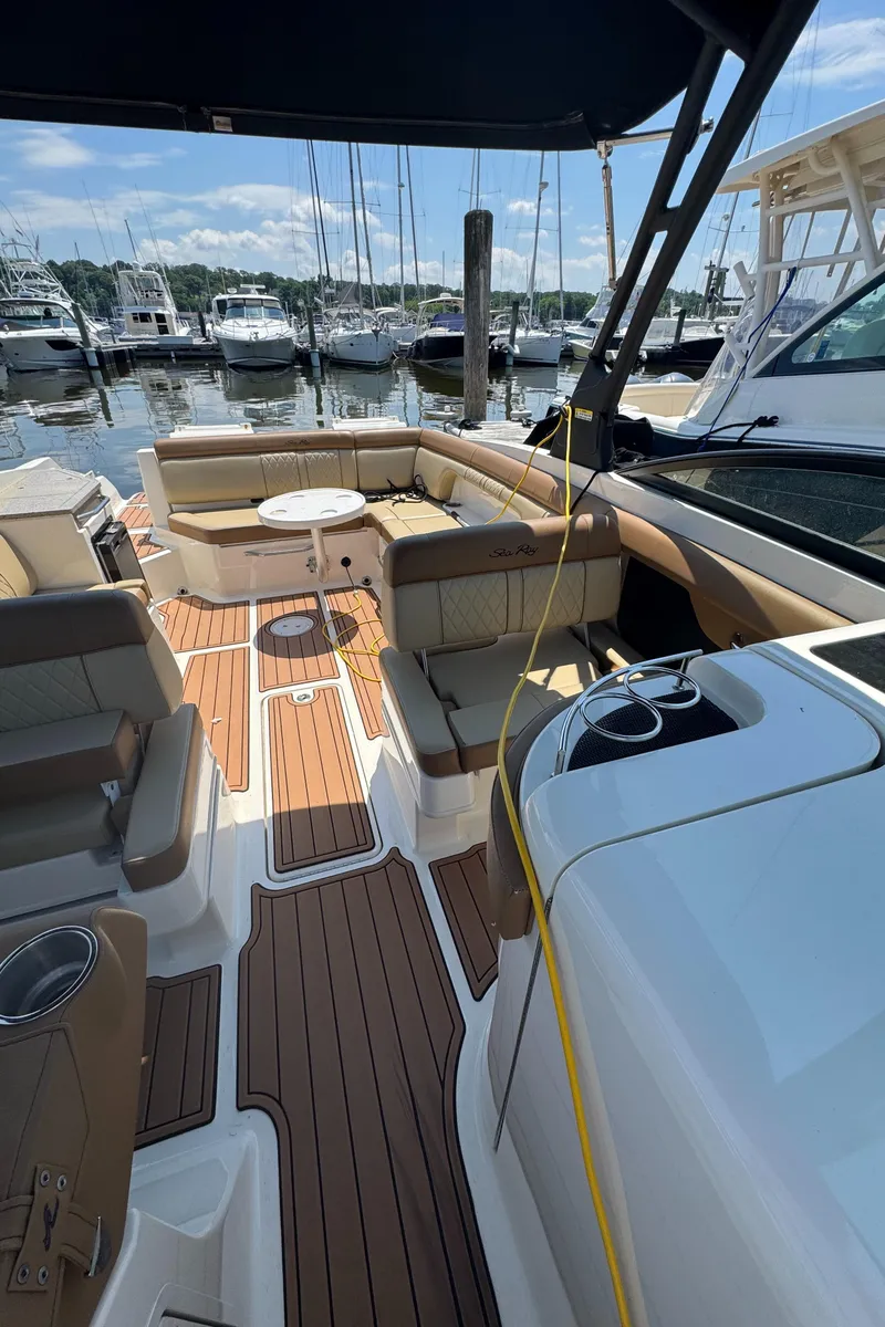 Slide: The Image of 2015 Sea Ray 290 Sundeck boat interior with seating and table, docked at marina. - 11