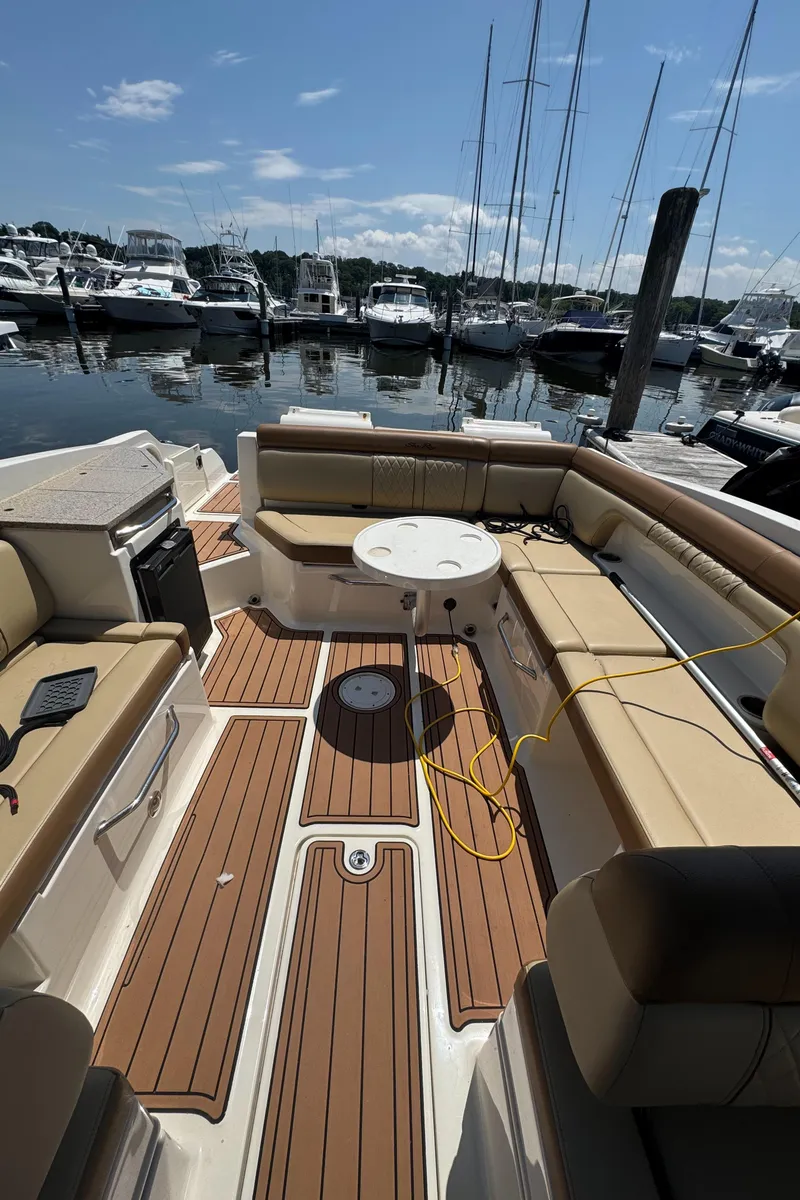 Slide: The Image of 2015 Sea Ray 290 Sundeck interior with seating and table, docked at marina. - 12