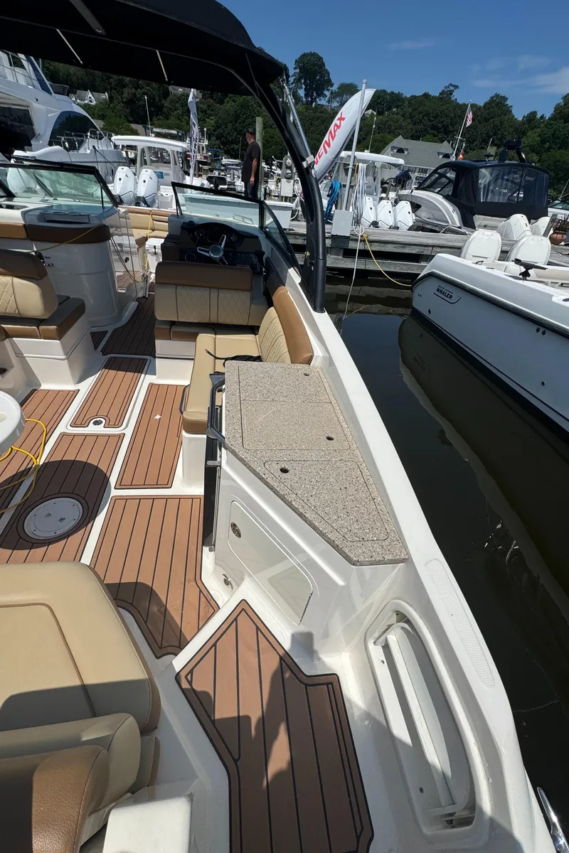 Slide: The Image of 2015 Sea Ray 290 Sundeck with spacious seating and elegant wood flooring at a marina. - 16