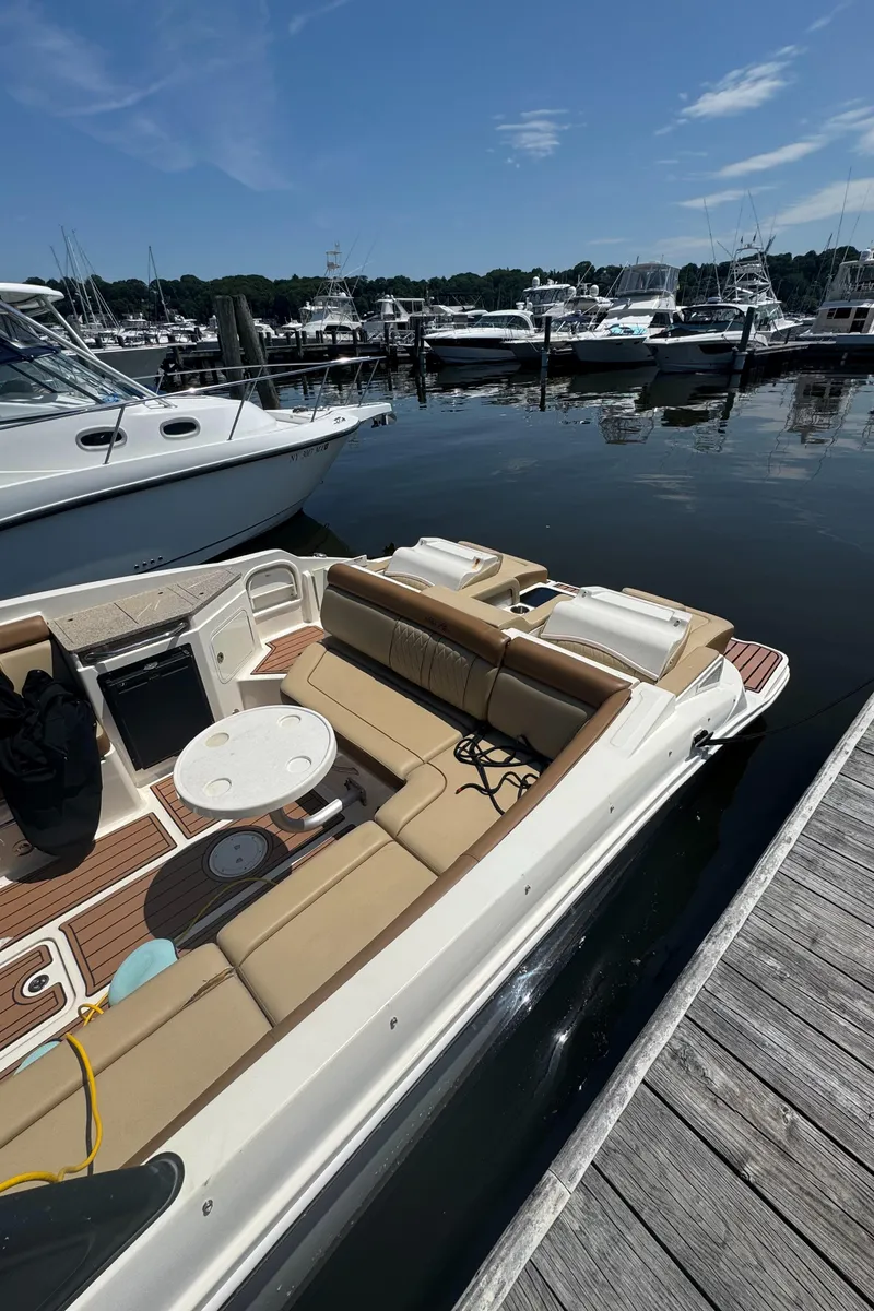 Slide: The Image of 2015 Sea Ray 290 Sundeck docked at marina, featuring spacious seating and sleek design. - 2