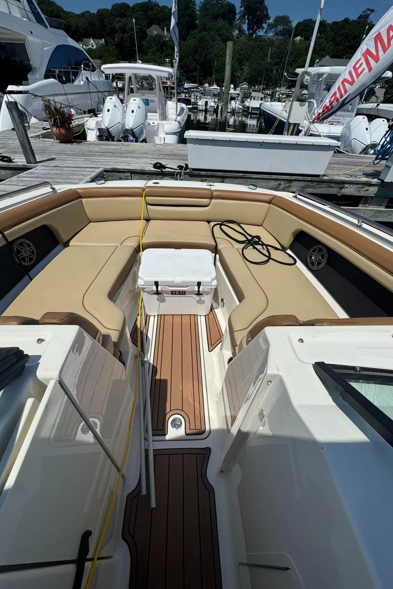 Slide: The Image of 2015 Sea Ray 290 Sundeck boat interior with tan seating and wooden flooring at a marina. - 9