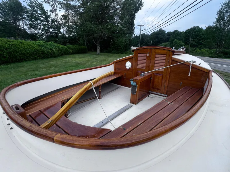 Slide: The Image of Wooden interior of a 2007 Arey's Pond 16 sailboat, featuring benches and a tiller. - 11