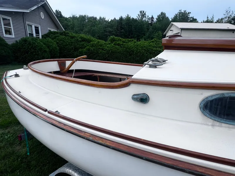 Slide: The Image of A 2007 Arey's Pond 16 sailboat with wooden trim, parked near a house and greenery. - 13