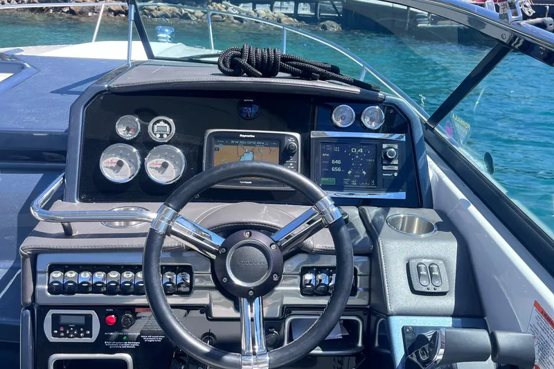 Slide: The Image of 2016 Formula 310 SS boat dashboard with steering wheel, gauges, and navigation system on a sunny day. - 8