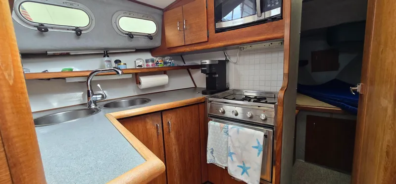 Slide: The Image of 1991 Bayliner 3288 Motoryacht kitchen with dual sinks, stove, and microwave. - 22