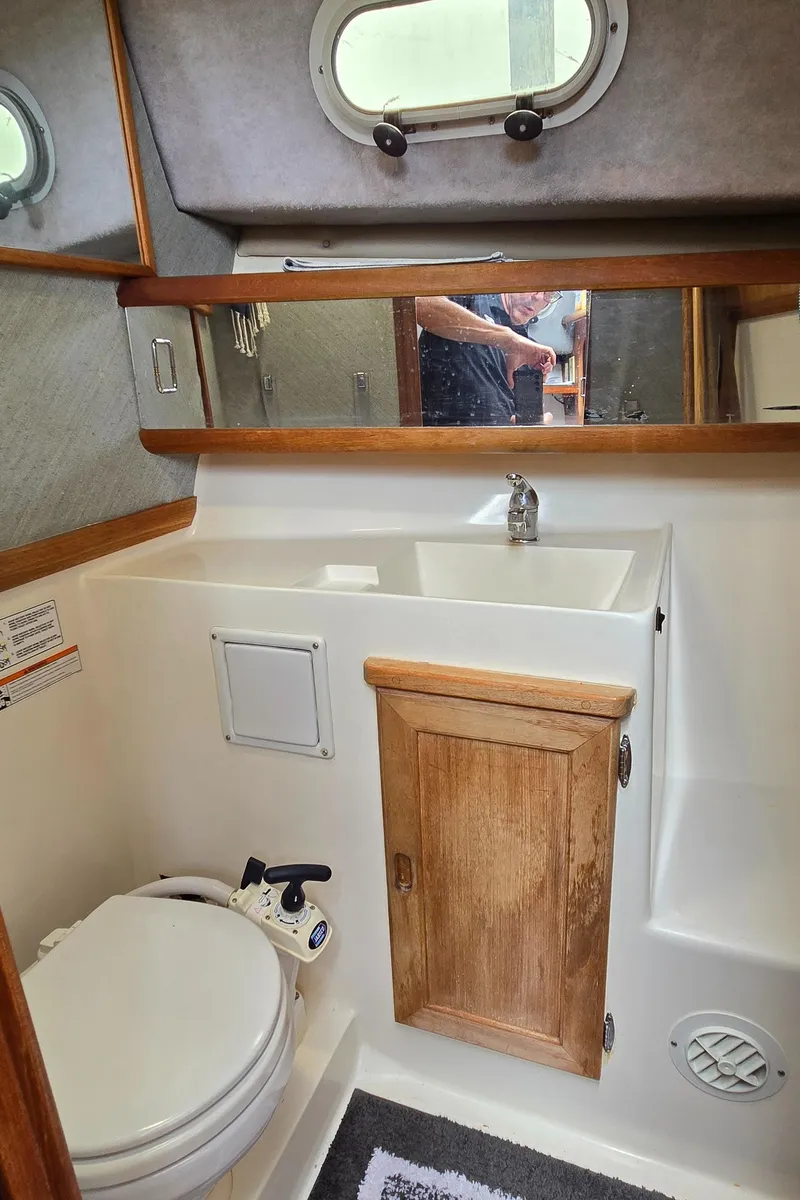Slide: The Image of Bathroom interior of 1991 Bayliner 3288 Motoryacht with sink, toilet, and wooden cabinet. - 33