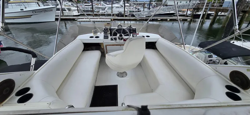 Slide: The Image of 1991 Bayliner 3288 Motoryacht cockpit with white seating and steering wheel, docked at marina. - 9