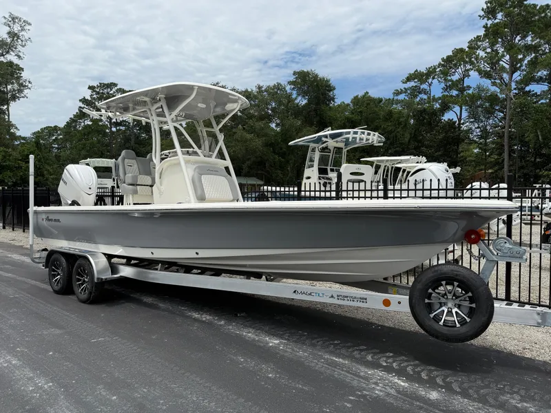 Slide: The Image of 2026 Avenger AV26 boat on trailer, parked outdoors near trees and fence. - 2