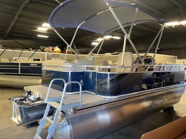 Slide: The Image of 2025 Tahoe Pontoon STX 1980 CR in a showroom, featuring a sleek design and canopy. - 2