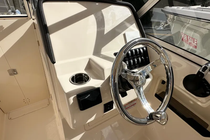 Slide: The Image of 2026 Grady-White Freedom 235 boat helm with chrome steering wheel and control panel. - 10