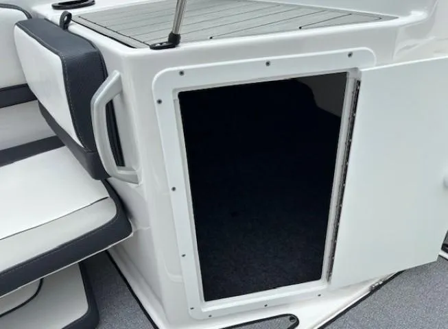 Slide: The Image of 2022 Yamaha AR195 boat storage compartment with open door, featuring white and black seating. - 15