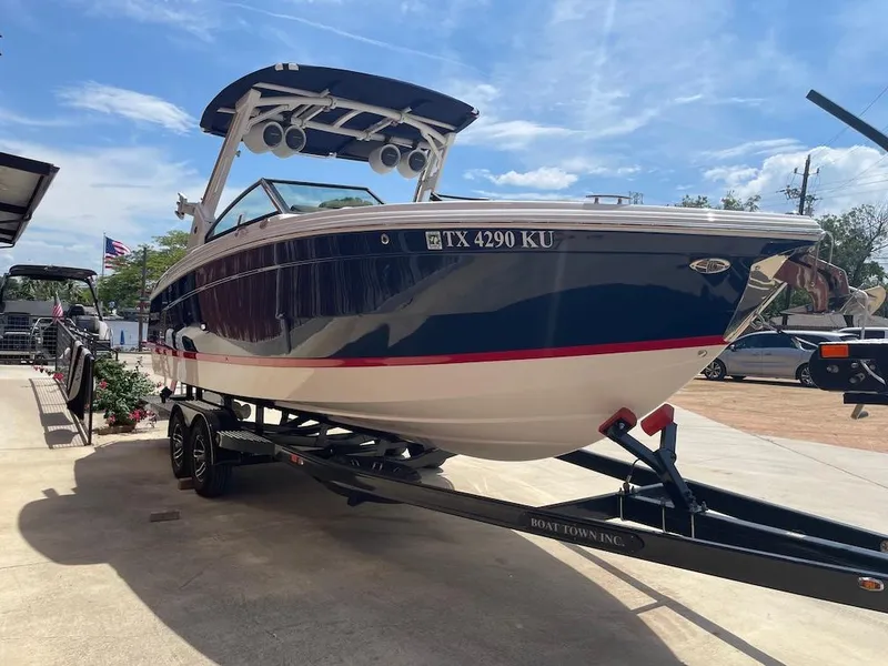 Slide: The Image of 2023 Cobalt R8 Surf boat on trailer, parked outdoors under a clear blue sky. - 2