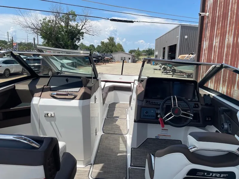 Slide: The Image of 2023 Cobalt R8 Surf boat interior with modern dashboard and seating, parked outdoors. - 6