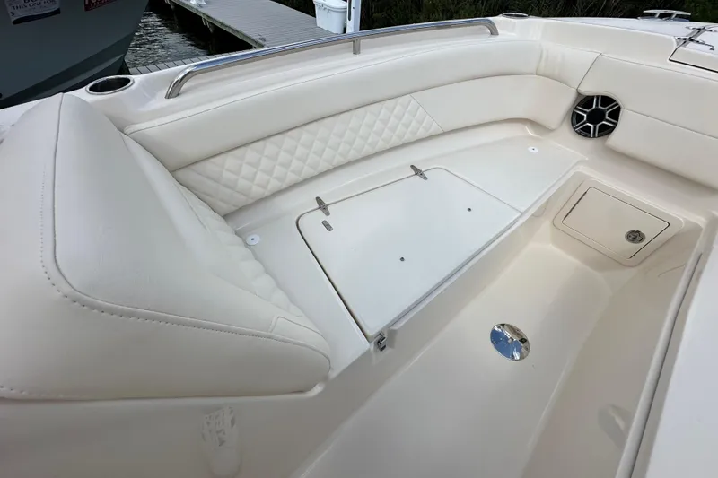 Slide: The Image of 2026 Grady-White Freedom 275 boat interior with white cushioned seating and storage compartments. - 21