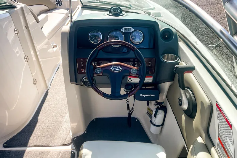 Slide: The Image of 2007 Sea Ray 260 Sundeck helm with steering wheel and Raymarine equipment. - 13